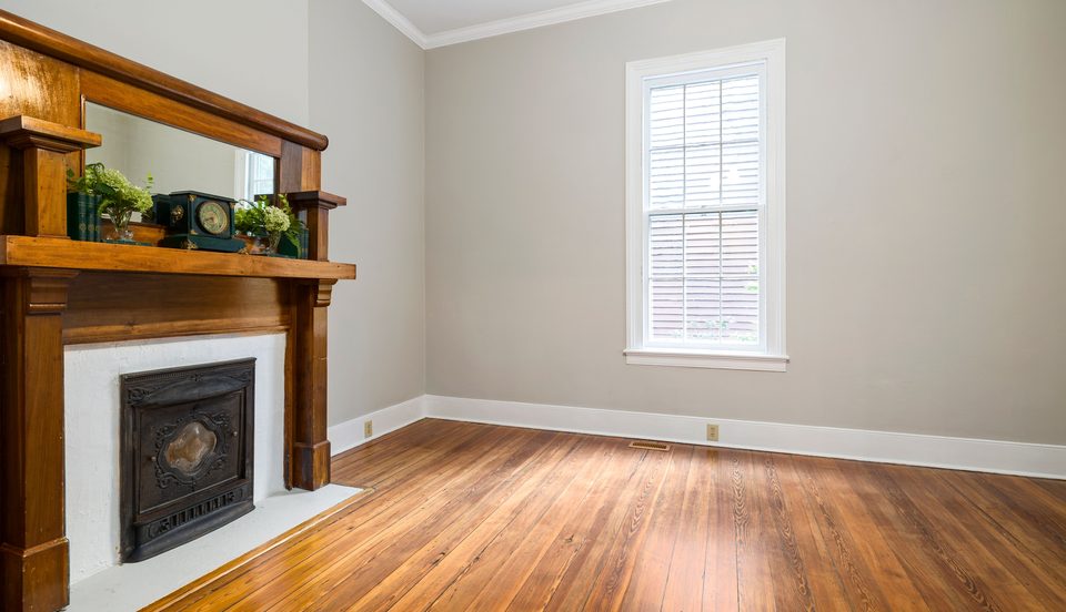 Refinished room with a wood mantel and hardwood floor
