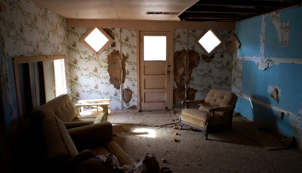 Room with peeling wallpaper and an open ceiling